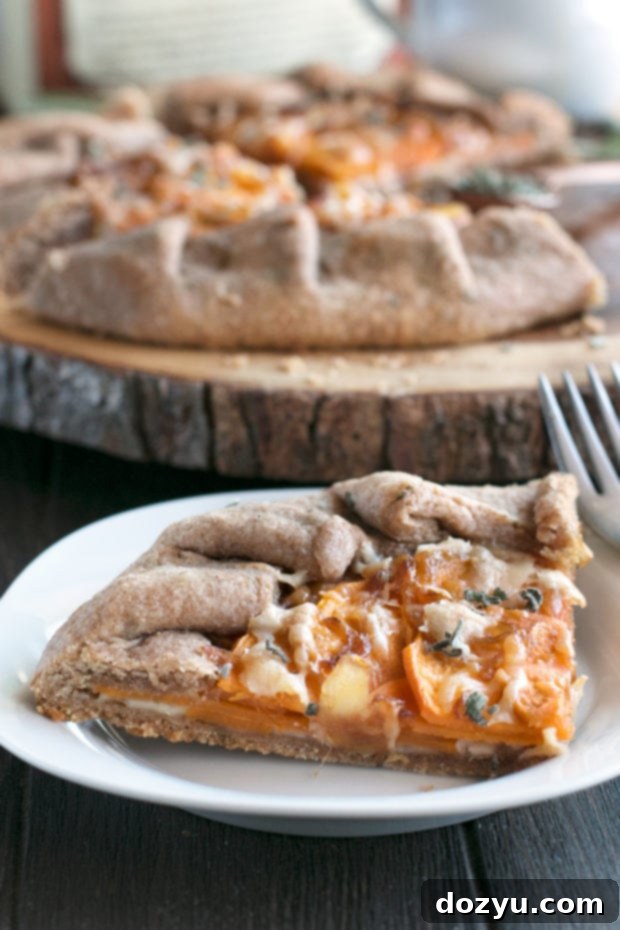 Three quarters view of a Whole Wheat Asiago Sweet Potato Galette on a cutting board, garnished with fresh sage leaves.