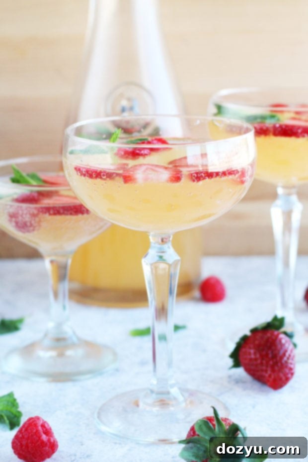 Effortless Bubbly Berry Sangria 2 Easy sangria with fresh strawberries and raspberries, garnished with mint in a coupe glass.