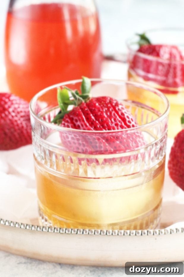 A pair of Strawberry Rhubarb Old Fashioned cocktails on a wooden surface