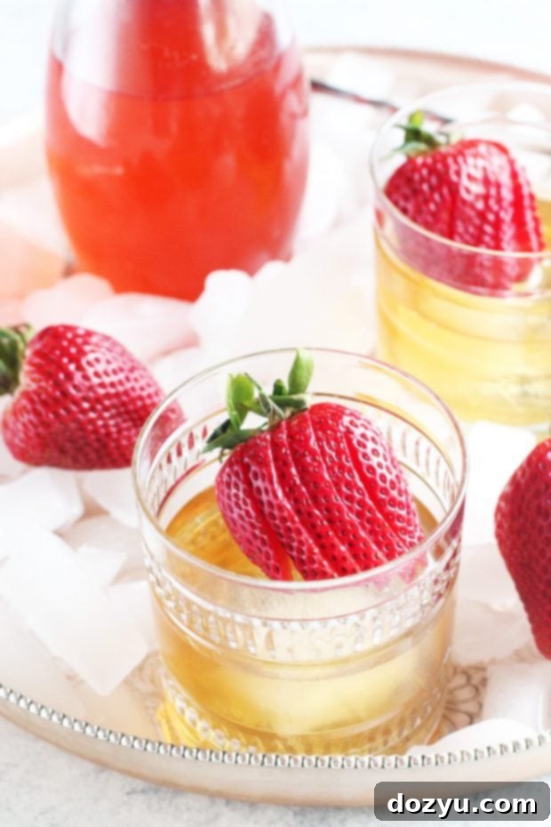 Two Strawberry Rhubarb Old Fashioned cocktails with ice and strawberry garnish