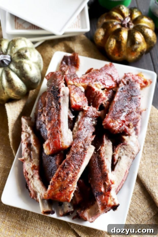 Two racks of Pumpkin Spice Dry Rub Ribs on a platter with herbs