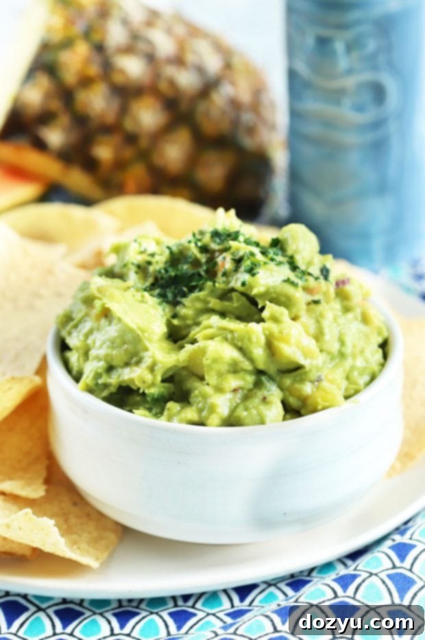 A vibrant bowl of Tropical Guacamole with fresh fruit chunks, ready to be served