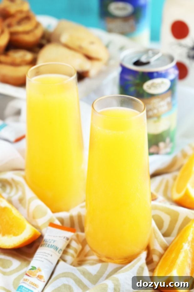 Exotic Mimosa Sparkler 8 A close-up of a Tropical Mimosa Mocktail, garnished with orange slices and a straw.