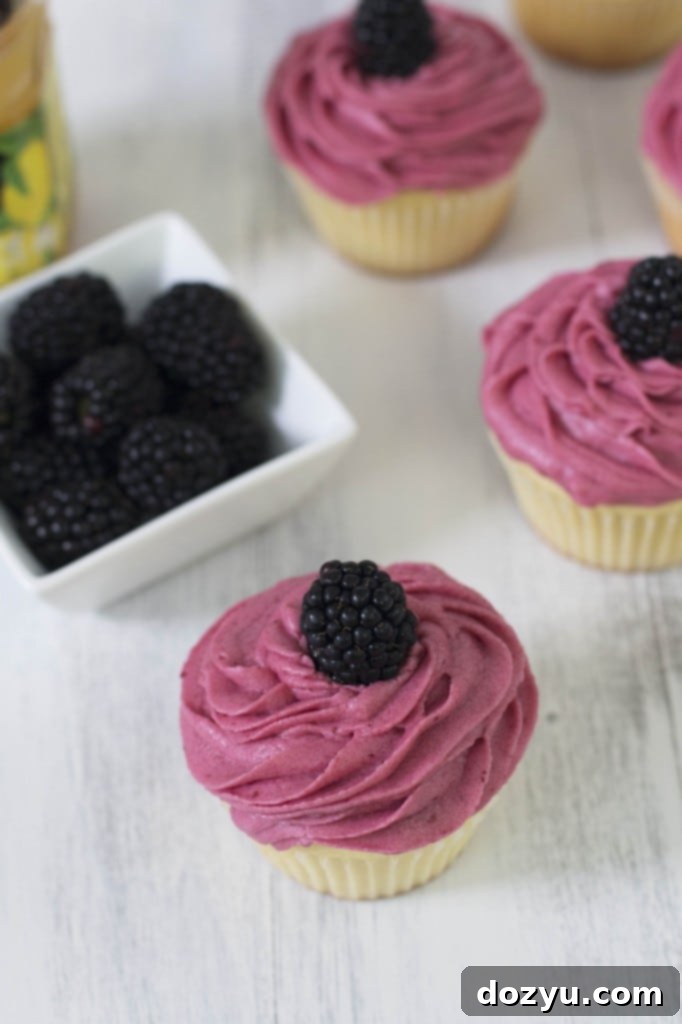 Delicious vanilla cupcakes with vibrant blackberry buttercream frosting and lemon curd filling, seen from above