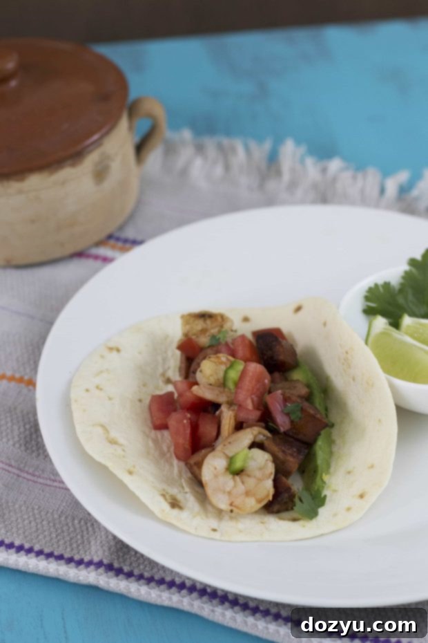 Spicy Summer Shrimp and Andouille Tacos 2 Shrimp and Andouille Sausage Summer Tacos arranged on a plate
