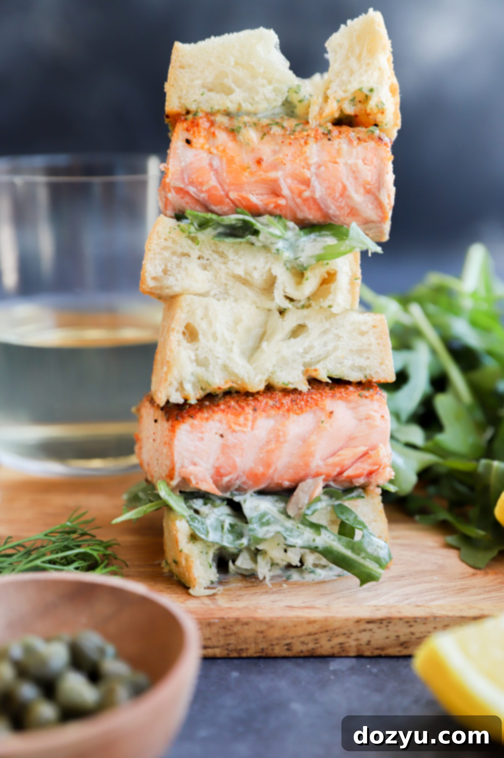 Elevated Salmon Sandwich with Herbed Dill Cream 10 Side view of a healthy salmon sandwich, cut in half to show layers