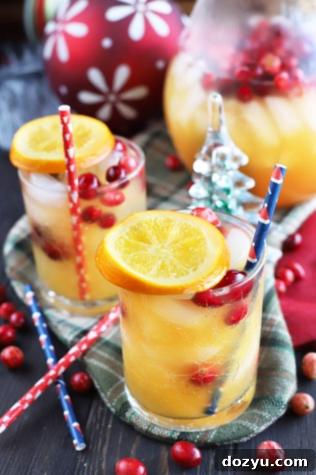 A close-up of the Spiced Tropical Holiday Champagne Punch, featuring its festive garnishes and vibrant color.
