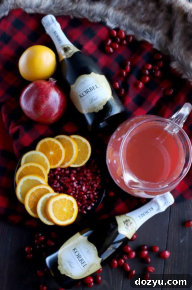 Close-up of a glass of Sparkling Holiday Brunch Punch with bubbles, garnished with a sprig of rosemary and cranberries.