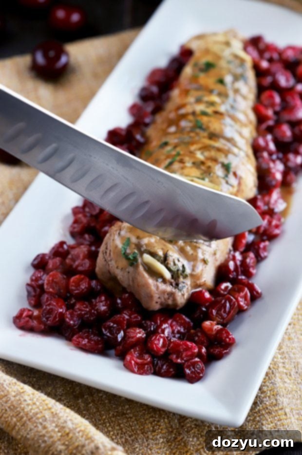 Detailed shot of hasselback cuts on pork tenderloin with garlic slices