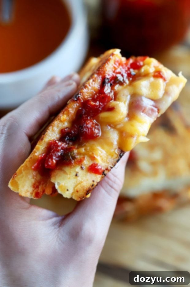 A freshly grilled Inverted French Baguette Grilled Cheese, cut in half to reveal the melted cheese and vibrant jam