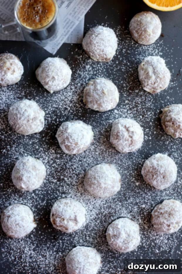 Orange Mocha Snowball Cookies 2 Mocha Orange Mexican Wedding Cookies - Overhead shot of several cookies on a white surface, lightly dusted with powdered sugar.