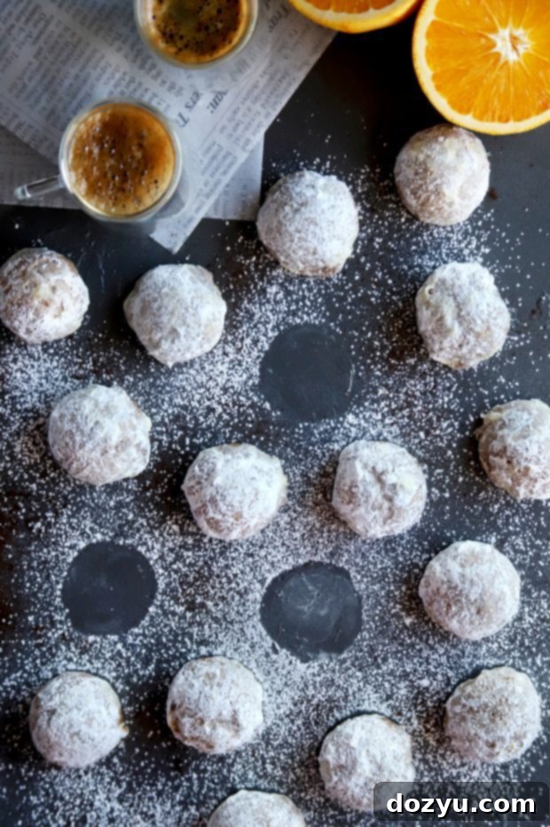 Orange Mocha Snowball Cookies 5 A plate of Mocha Orange Mexican Wedding Cookies with a cup of coffee in the background, suggesting a perfect pairing.