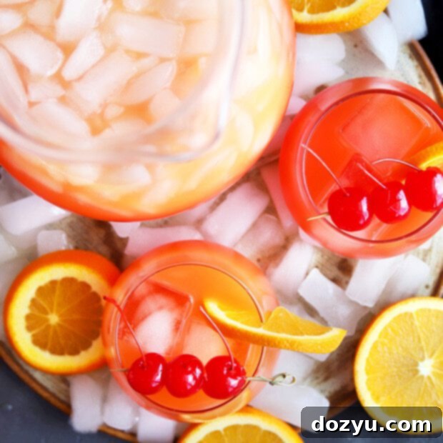A vibrant pitcher of Peach Tequila Sunrise Punch, ready to serve