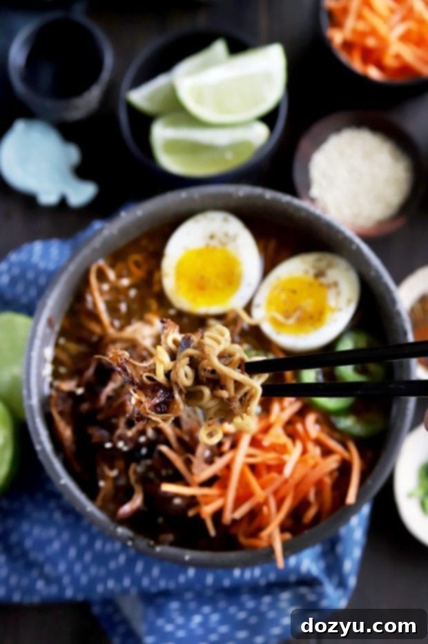 Ultimate Spicy Instant Pot Pork Ramen 5 Picking up ramen noodles with chopsticks from a flavorful broth