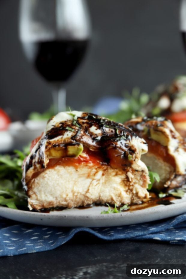 Close-up of grilled avocado caprese chicken cut in half on a plate