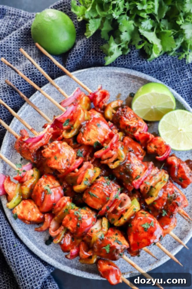 Smoky Chipotle Grilled Chicken Skewers 2 Plate of grilled bbq chicken kabobs with lime halves and cilantro bunch