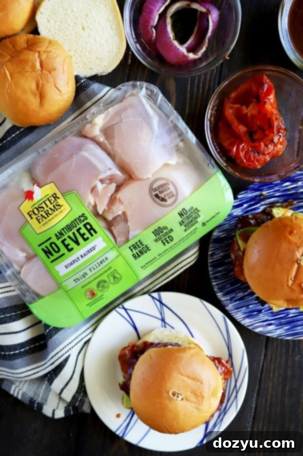 Close-up of a hand assembling a grilled chicken sandwich with BBQ sauce, demonstrating the layering process.