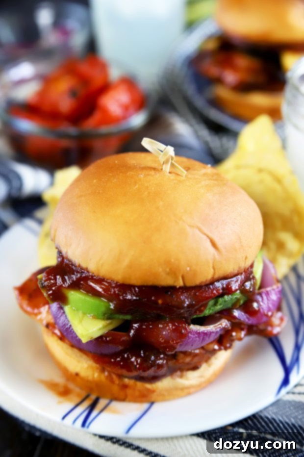 Grilled chicken thigh on a toasted bun, topped with spicy BBQ sauce, ready to be completed into a sandwich.