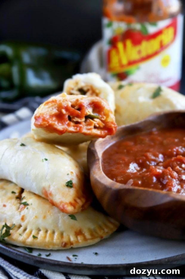 Poblano-Infused Chicken Enchilada Empanadas 8 A close-up of a beautifully baked Poblano Enchilada Chicken Empanada being dipped into a vibrant bowl of LA VICTORIA® salsa, ready to be eaten.