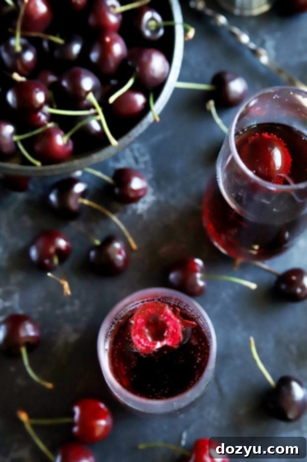 Fresh cherries in a bowl surround elegant champagne flutes filled with Cherry Rosé Mimosas