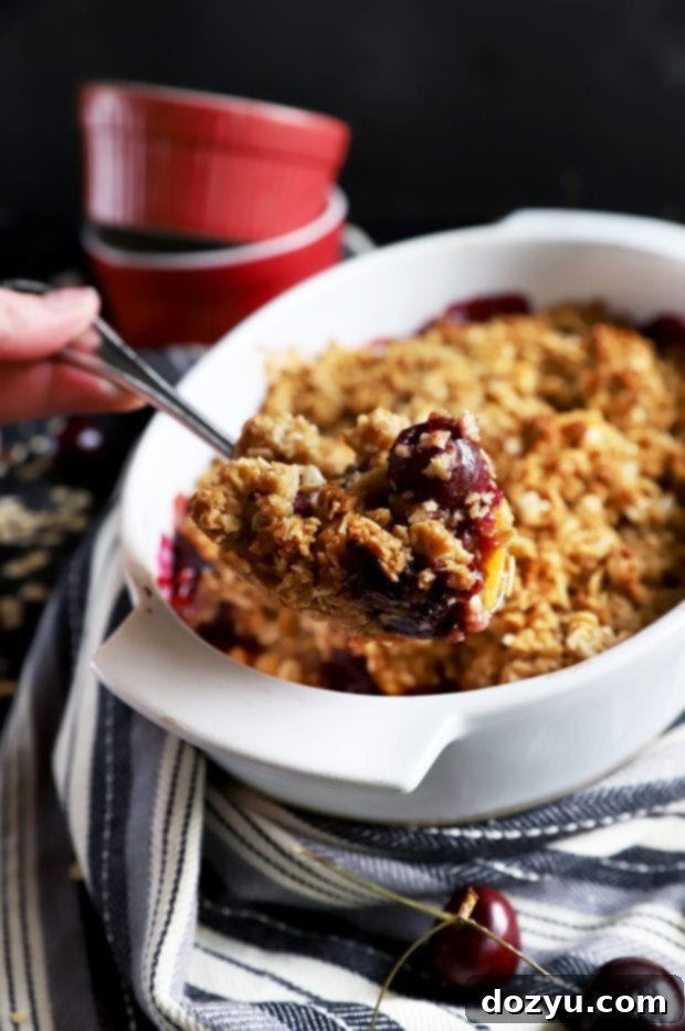 Sweet & Boozy Bourbon Cherry Peach Crumble 5 Lifting out a fruit crumble from baking dish