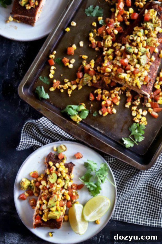Pan-Seared Salmon with Charred Corn, Avocado and Tomato Salsa 3 Salmon for dinner on a plate with charred corn salsa, lime wedges, and fresh herbs