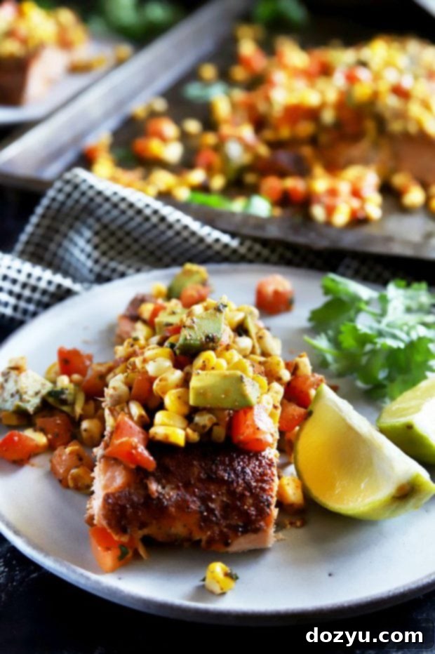 Pan-Seared Salmon with Charred Corn, Avocado and Tomato Salsa 4 Individual grilled salmon filet on a white plate with lime and a generous portion of charred corn avocado tomato salsa