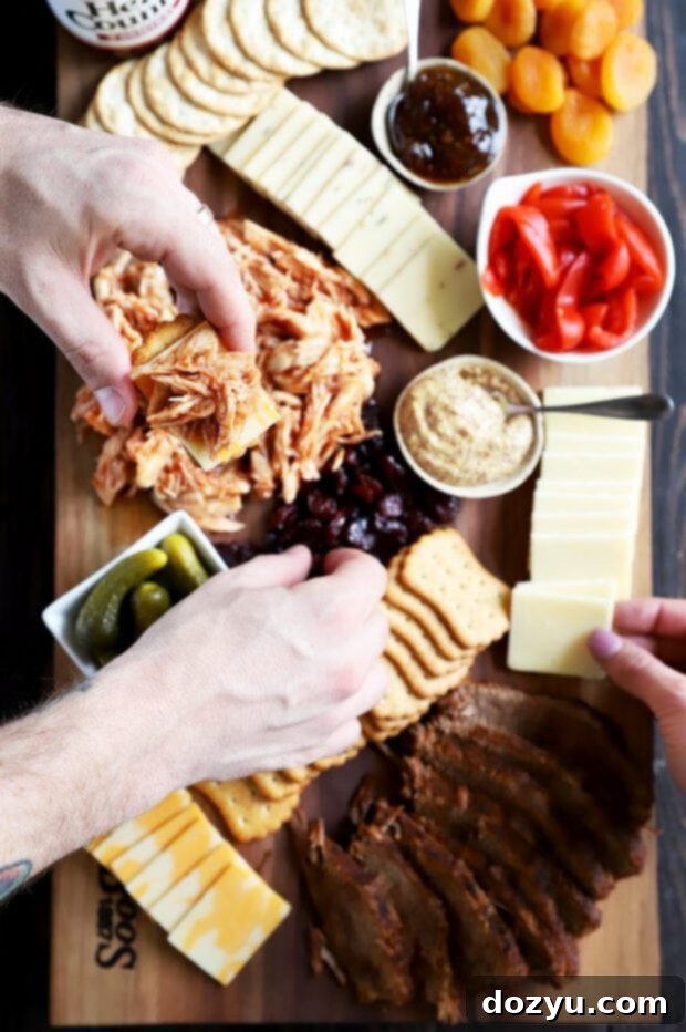 Hands reaching for BBQ meat, cheese, and crackers on the board