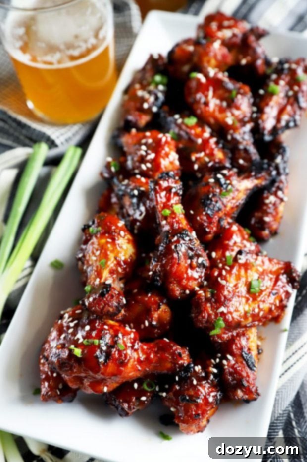 Sticky Crispy Korean BBQ Wings 6 Side view of crispy Korean BBQ chicken wings on a plate with beer in the background