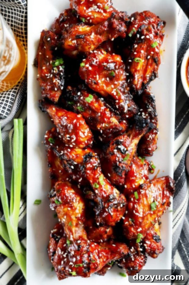 Sticky Crispy Korean BBQ Wings 8 Crispy Korean BBQ chicken wings garnished with sesame seeds and green onions on a white plate