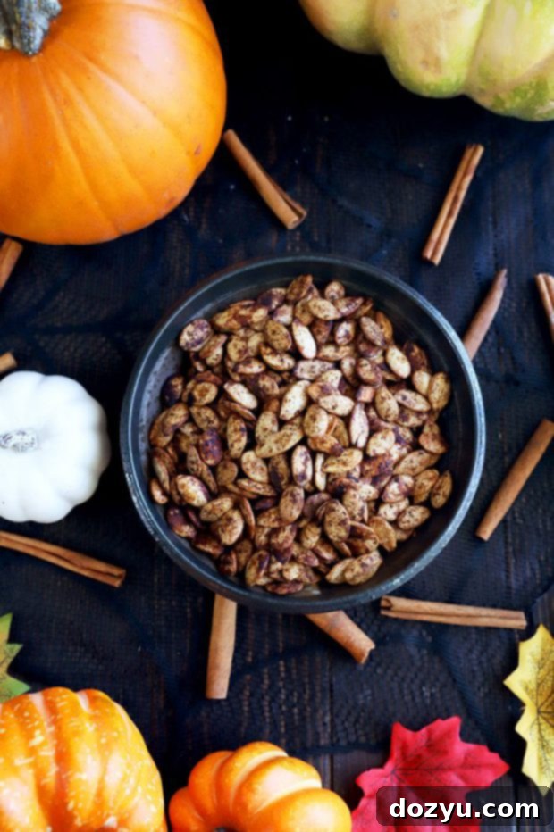Close-up photo of perfectly roasted pumpkin seeds with visible spices in a rustic white bowl, showcasing their golden crispness and inviting texture.