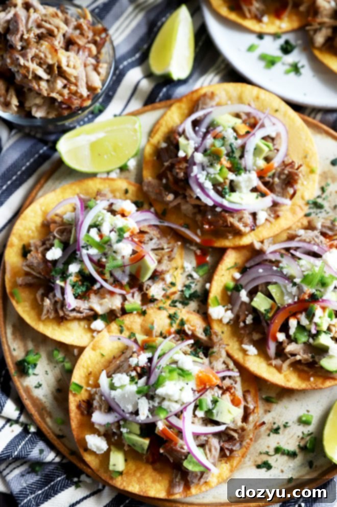 A large platter filled with beautifully assembled crispy pork carnitas tostadas, ready to serve.