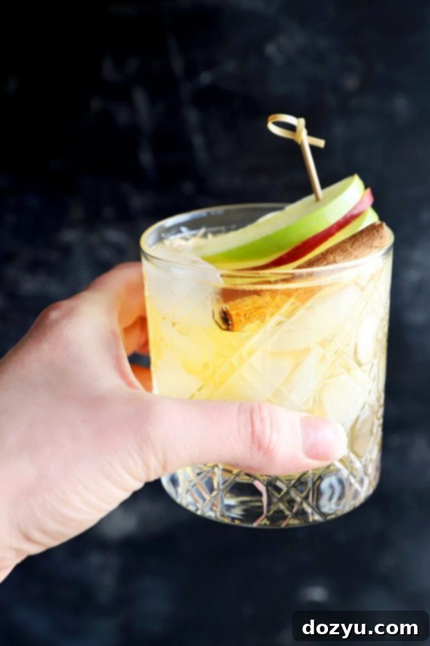 Effortless Apple Pie Sparkler 4 Close-up of a hand holding a chilled glass of homemade apple pie sparkling sangria