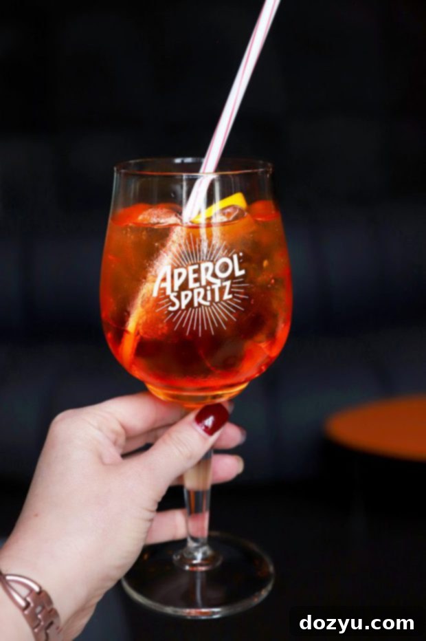 Hand holding an Aperol Spritz with Milan's Duomo di Milano in the background, a perfect guide to Milan moment