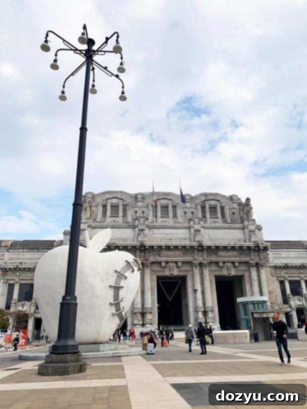 Milan square with historic buildings and people near a train station