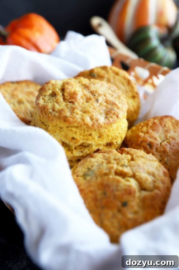 A basket of freshly baked pumpkin sage biscuits, highlighting their flaky texture and golden-brown tops.