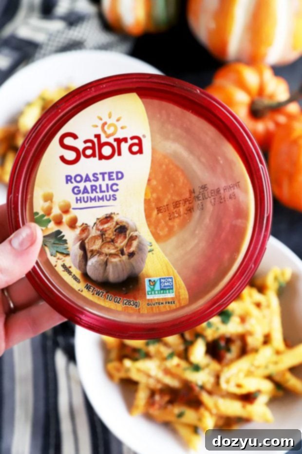 Garlic-Roasted Pumpkin Hummus Pasta 5 Hand holding a tub of Sabra Roasted Garlic Hummus
