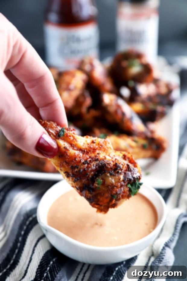 Smoky Dry-Rubbed Wings with Zesty BBQ Blue Cheese 5 Close-up of a dry rub chicken wing being dipped into a bowl of BBQ blue cheese sauce