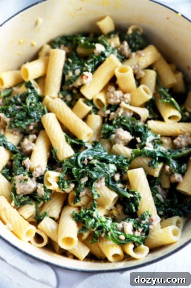 Rich Creamy Sausage Kale Rigatoni 3 Creamy kale rigatoni pasta being stirred in a large pot, ready to be served.