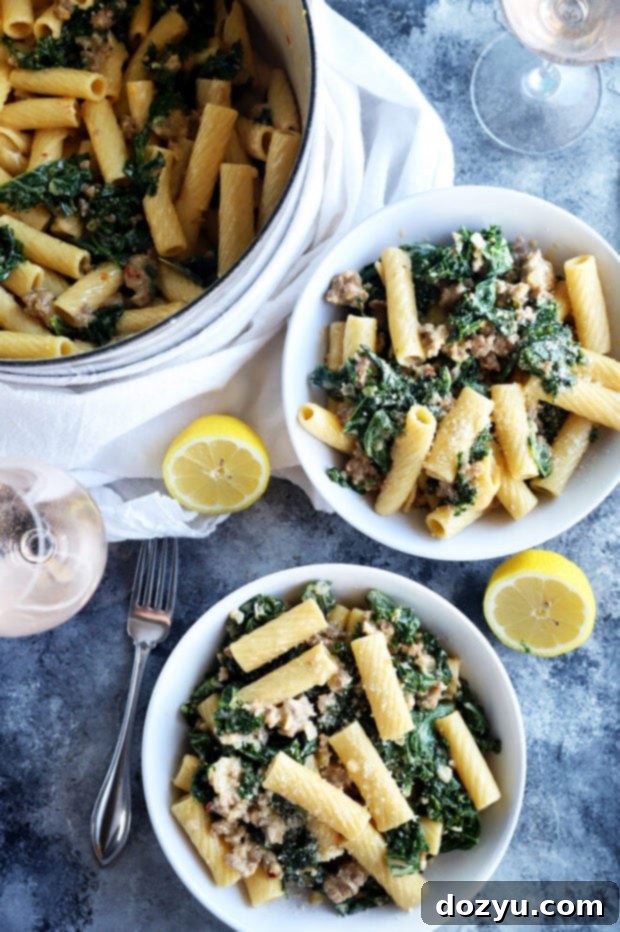 Rich Creamy Sausage Kale Rigatoni 4 Two bowls of creamy sausage kale rigatoni pasta, garnished with lemon slices and fresh parsley.