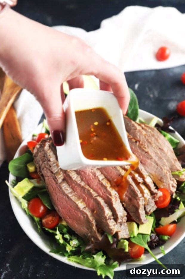 Umami Steak & Avocado Power Bowl 9 Pouring miso dressing over a vibrant steak salad in a large bowl