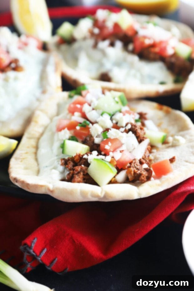 Savory Greek Beef Wraps 6 A single Greek pita on a plate with fresh toppings and tzatziki