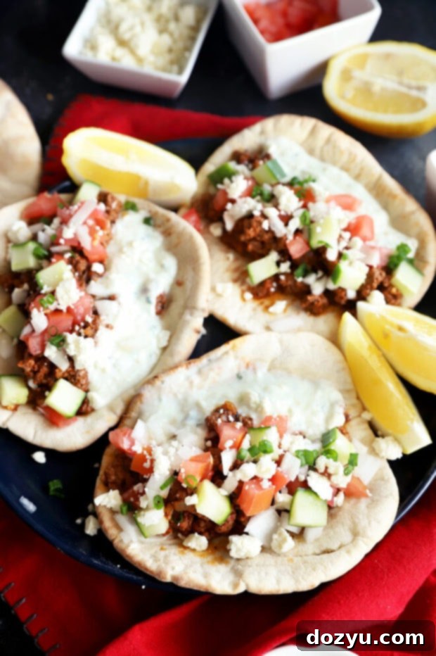 Savory Greek Beef Wraps 9 Greek beef pitas on a plate, garnished with fresh herbs and a lemon wedge
