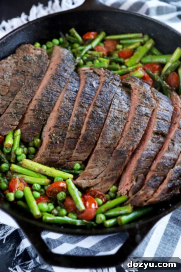 Steak searing in a skillet with vegetables added to the side