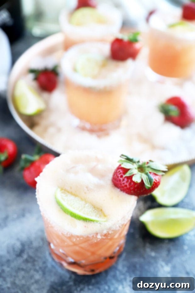 Close-up of a Strawberry Margarita Mimosa cocktail in a fluted glass, garnished with a strawberry and lime slice.