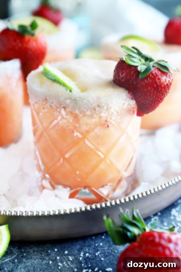 Side view of a Strawberry Margarita Mimosa, showing the layers of liquid and the garnish of strawberry and lime.