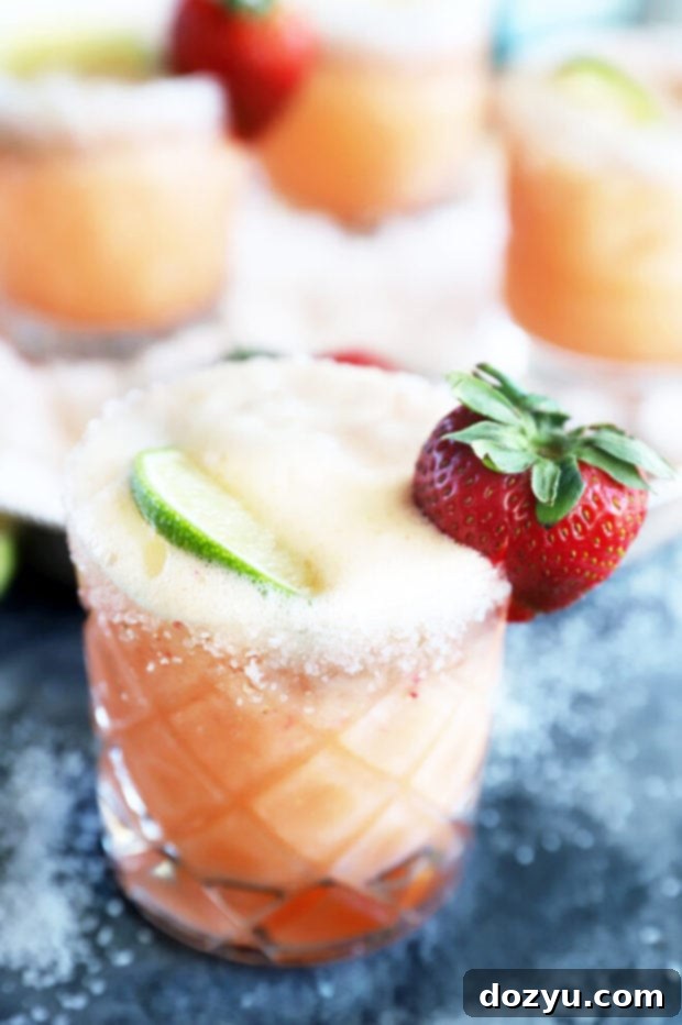 Close-up of a Strawberry Margarita Mimosa cocktail with a salted rim and garnishes.