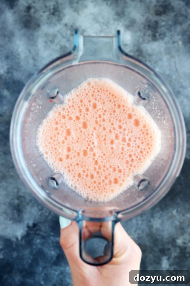 Blender with fresh strawberries and orange juice, ready for blending.