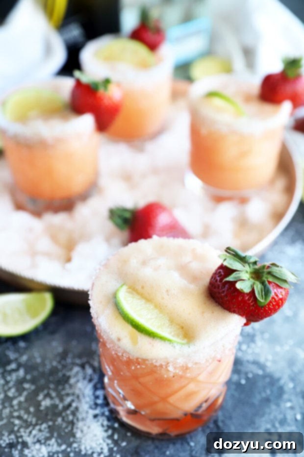 A mimosa cocktail in a glass, with a salted rim and a strawberry garnish.