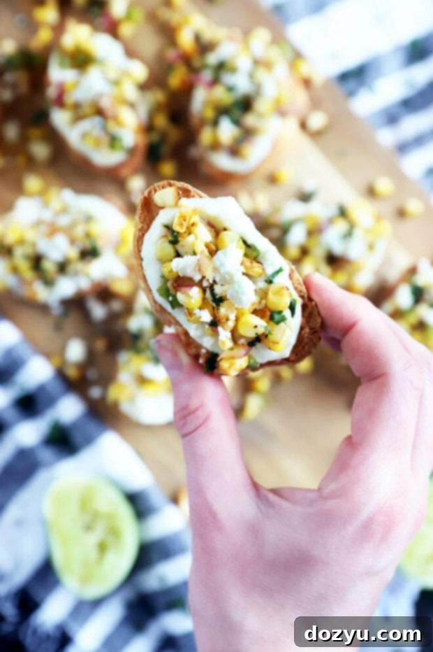 Zesty Grilled Elote Crostini 8 A hand reaching for a grilled mexican corn crostini from a serving tray